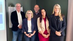 Fem personer står uppställda mot en grön vägg