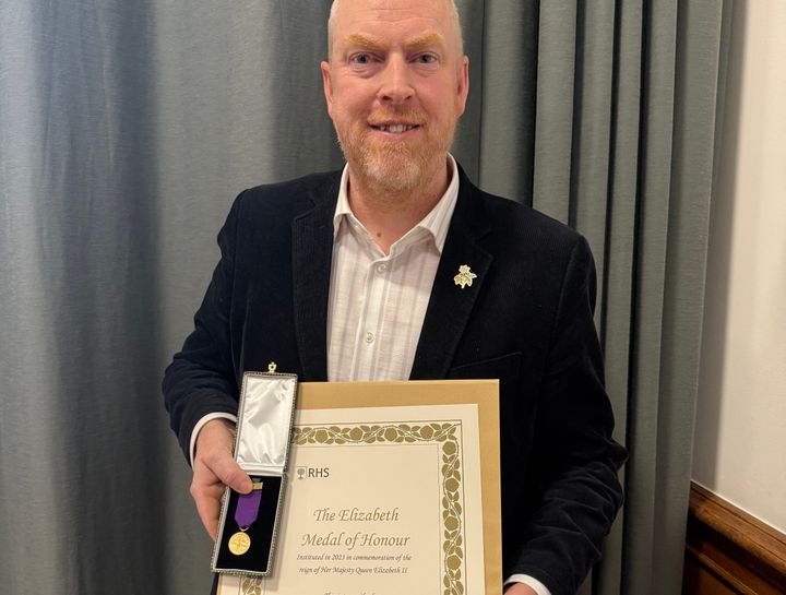 En person håller en medalj och ett diplom.