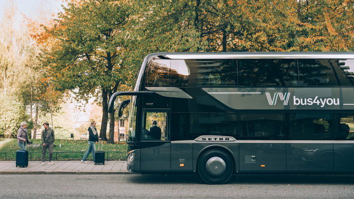 Buss från Vy bus4you står på en väg med träd i bakgrunden.