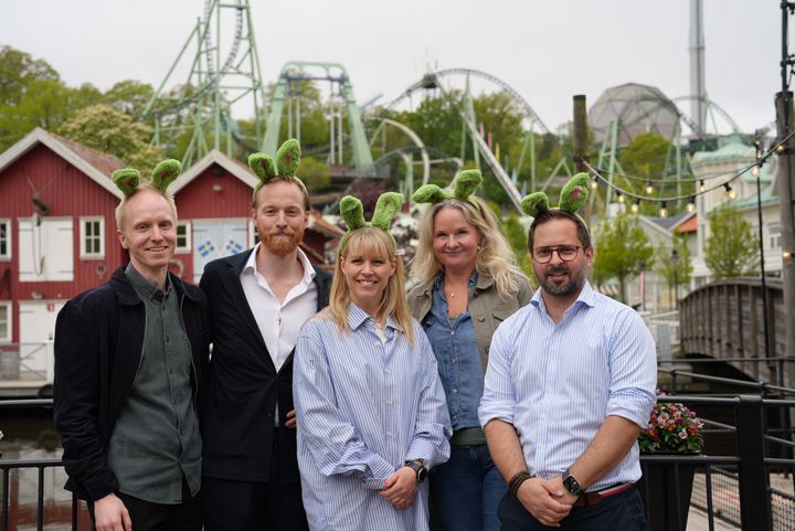 Fem personer framför en bakgrund med berg- och dalbanor.