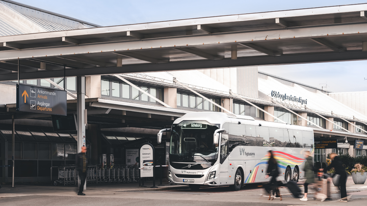 Vy flygbussarna utanför en terminal på Landvetter flygplats med gående människor i förgrunden.