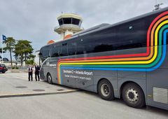 En eldriven flygbuss från Vy på en parkeringsplats i Visby. Flygplatstornet syns i bakgrunden.