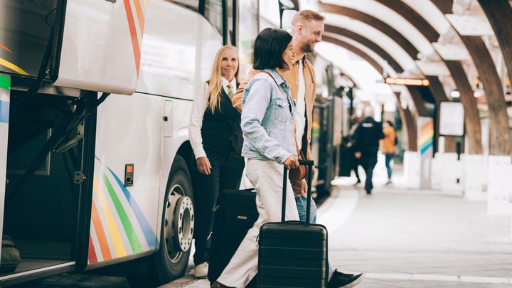 Resenärer kliver av en buss med bagage vid Arlanda flygplats.