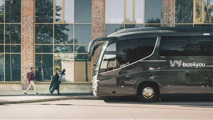 Vy bus4you vid en vägg. Två personer som går mot bussen.