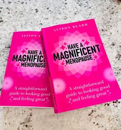 Två exemplar av boken "Have a Magnificent Menopause" ligger på en köksbänk – en inbjudande scen för läsning och inspiration.