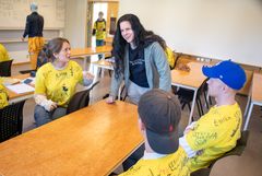 Bild på kursledaren Olow Sande i samspråk med två studenter i klassrummet