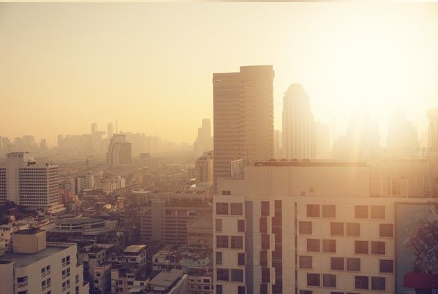 Stadssilhuett i solljus med höga byggnader i förgrunden.