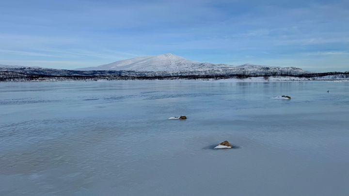 En frusen sjö med snöklädda fjäll i bakgrunden i Stordalen, Abisko.