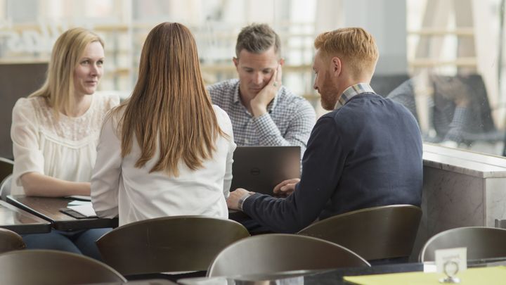Fyra personer sitter vid ett bord och diskuterar.