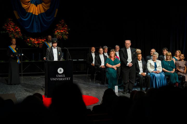 Personer sitter på en scen under Århögtidens ceremoni.