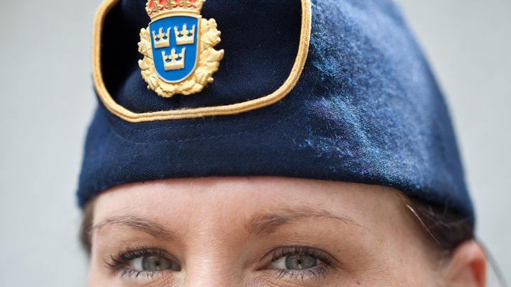 En kvinna i närbild där ögonen och en polismössa syns.
