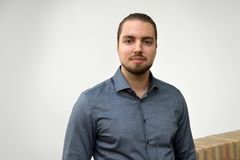 En person med blå skjorta står framför en vit bakgrund.