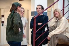 Fyra studenter samtalar och skrattar i ett trapphus.