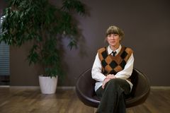 En person sitter i en stol framför en växt.