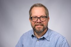 Person i glasögon och skägg som bär en ljusblå skjorta