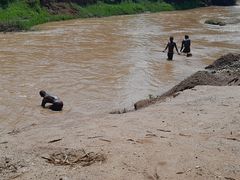 Bild på flod i Rwanda och tre vadande personer
