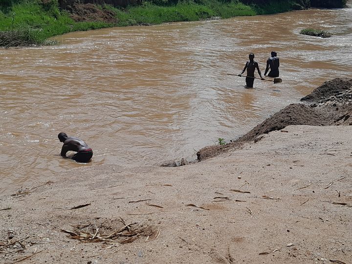 Bild på flod i Rwanda och tre vadande personer