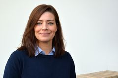 Kvinna med brunt hår och blå tröja ler mot kameran.
