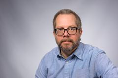 Porträtt på man framför grå vägg