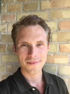 Porträtt av Mattias Brunström framför en tegelvägg.