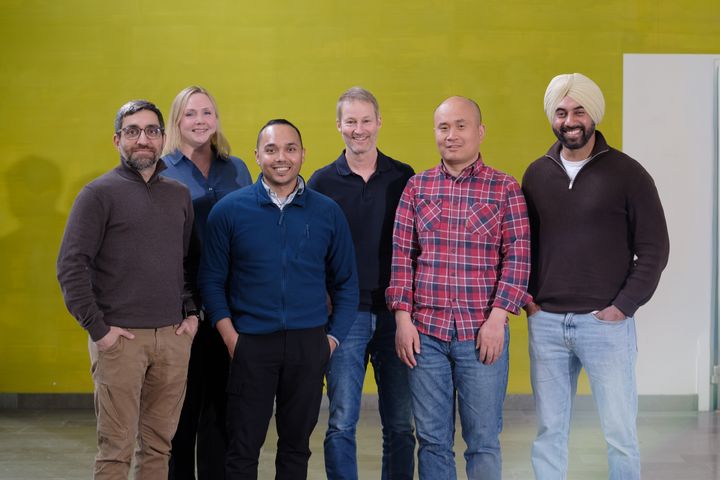Photo of the research group at Umeå University standing against a green wall