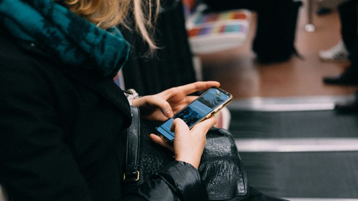 A person sitting and using a smartphone on public transport.