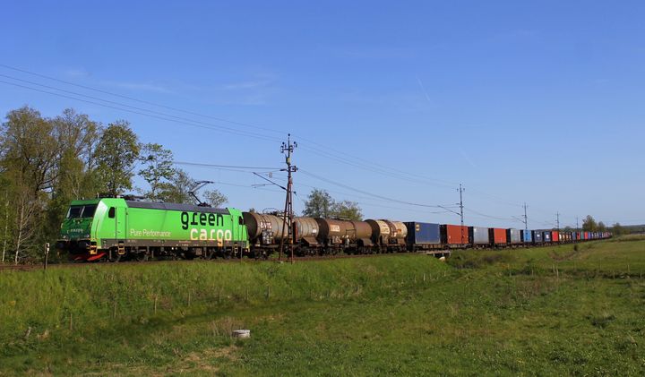 Green Cargos godståg passerar genom Skåne en vacker sommardag.