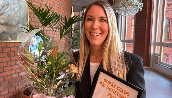 Evelina Brofjärd håller en blombukett och en utmärkelse märkt "BORÅS STADS RÄTTIGHETSPRIS 2025".