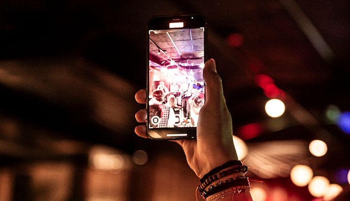 En person håller upp en mobiltelefon och tar ett foto på en livlig och färgglad inomhusmiljö.