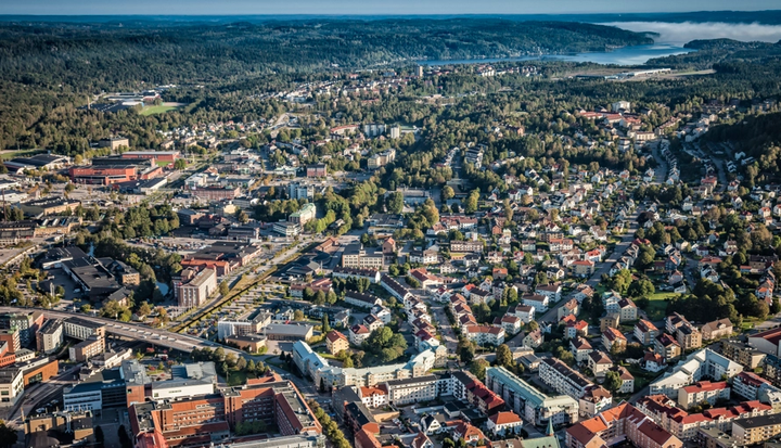 Flygfoto över en stad med många hus, byggnader och omgivande skogbevuxna områden.