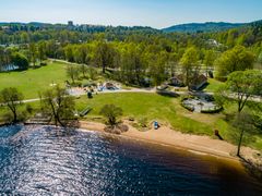 Flygfoto av en badplats i Borås med en strand, lekpark och grönska.