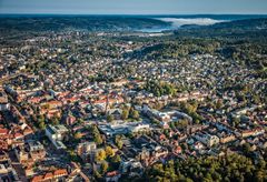 Flygfoto av stadsmiljö i Borås med omgivande skog och vatten i bakgrunden.