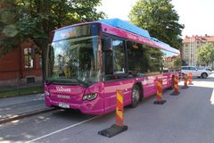 Valbuss parkerad vid trottoaren med trafikhinder runt omkring.