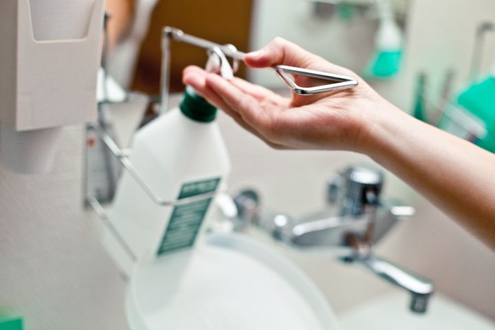 Person tvättar händerna under en tvålpump vid ett handfat.
