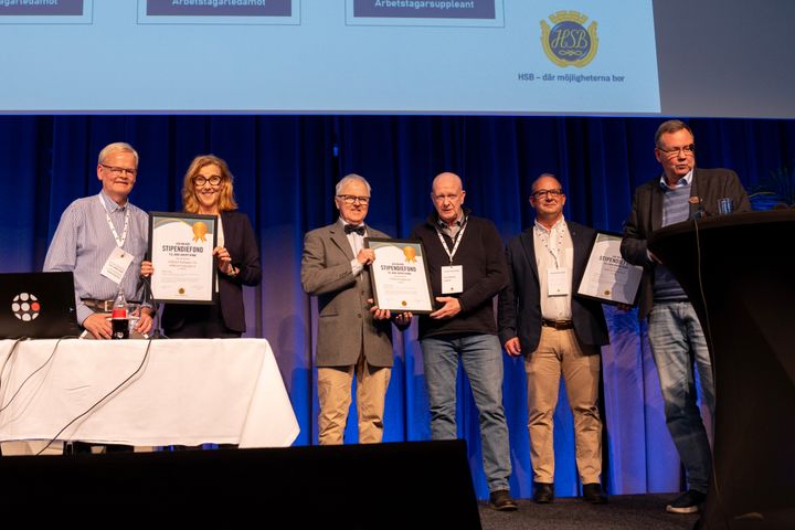 Sex personer står på en scen och håller diplom.