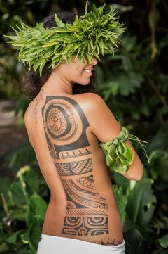 Vi Teruria Taimanas tatuerade rygg i håret bär hon en grön krans.