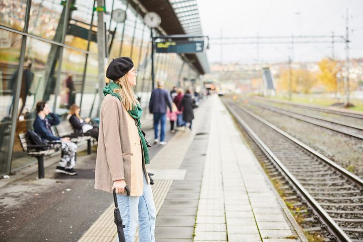 En kvinna står på en perrong och väntar på tåget.