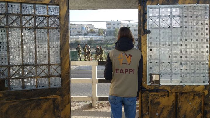 Följeslagare på plats vid porten till en skola där elever dagligen möter israeliska soldater och bosättare.