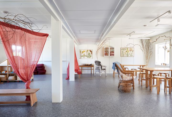 Valoisa%20sis%E4tila%2C%20jossa%20puup%F6yti%E4%2C%20tuoleja%20ja%20leikkialue%20verhoineen.