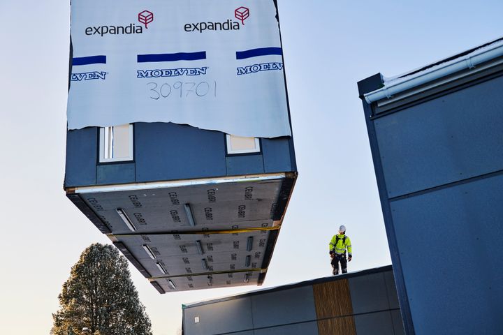 Moduulirakennuksen%20osa%20nostetaan%20paikalleen%20ty%F6maalla%2C%20ty%F6ntekij%E4%20ohjaa%20asennusta%20rakennuksen%20katolta.