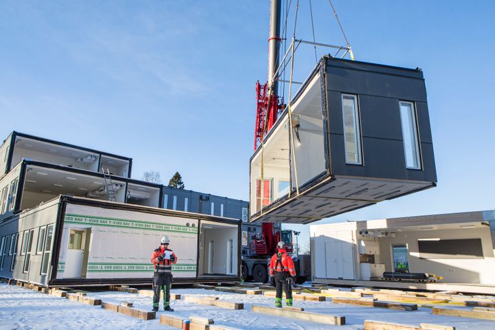 Nosturi%20laskee%20moduulirakennuksen%20osaa%20paikoilleen%20ty%F6maalla%2C%20ty%F6ntekij%E4t%20ohjaavat%20asennusta%20lumisella%20tontilla.