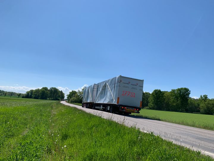 Rekka%20kuljettaa%20moduulirakennuksen%20osia%20maantiell%E4%20peltojen%20keskell%E4.