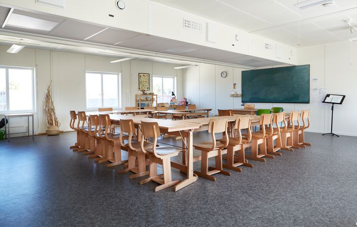 Valoisa%20luokkahuone%2C%20jossa%20on%20riveitt%E4in%20puisia%20pulpetteja%20ja%20tuoleja%2C%20suuri%20liitutaulu%20sein%E4ll%E4%20sek%E4%20ikkunoista%20tulevaa%20luonnonvaloa.