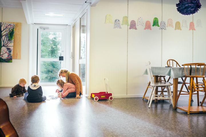 P%E4iv%E4kotitila%2C%20jossa%20aikuinen%20ja%20lapset%20istuvat%20lattialla%20leikkim%E4ss%E4%3B%20taustalla%20ruokap%F6yt%E4%20ja%20sein%E4ll%E4%20lasten%20askarteluja.