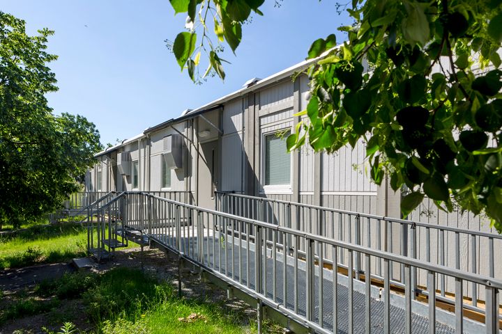 Vaalea%20moduulirakennus%2C%20jonka%20sis%E4%E4nk%E4ynnille%20johtaa%20pitk%E4%20esteet%F6n%20luiska%20kaiteineen.%20Rakennus%20sijaitsee%20vehre%E4ll%E4%20alueella%20puiden%20ja%20nurmikon%20keskell%E4%20kes%E4isess%E4%20s%E4%E4ss%E4.