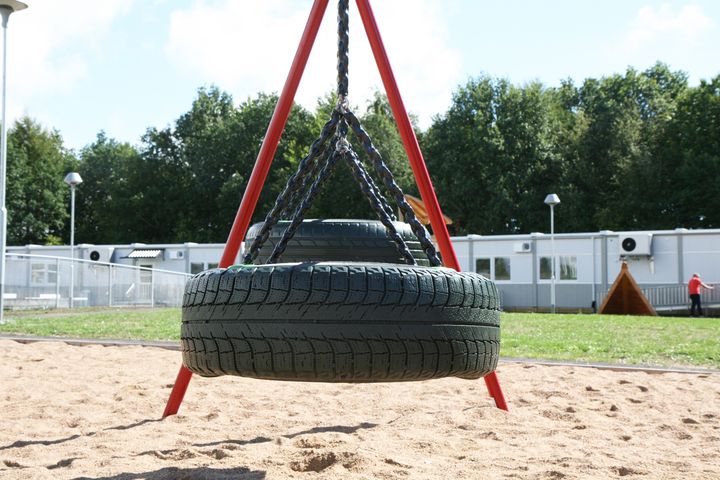 Rengaskeinu%20hiekkapohjaisella%20leikkialueella%20koulun%20pihalla.%20Taustalla%20n%E4kyy%20siirtokelpoisista%20moduuleista%20rakennettu%20koulurakennus%2C%20joka%20toimii%20v%E4ist%F6tilana%20koulun%20peruskorjauksen%20aikana.