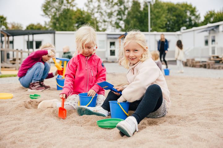 Kaksi%20lasta%20leikkii%20hiekkalaatikolla%20moduulirakennuksen%20edess%E4.