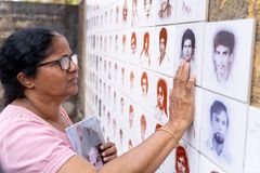 A woman touching portraits on a monument for disappeared people in Seeduwa, Sri Lanka.