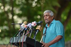 Brito Fernando håller ett tal. Han står vid ett podium med massor av mikrofoner.