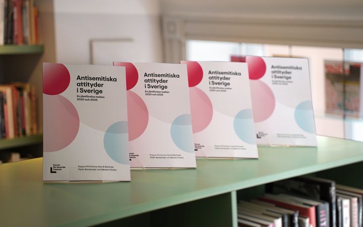 Alt text: Four copies of the report "Antisemitic Attitudes in Sweden: A Comparison Between 2020 and 2025" are displayed on a shelf.